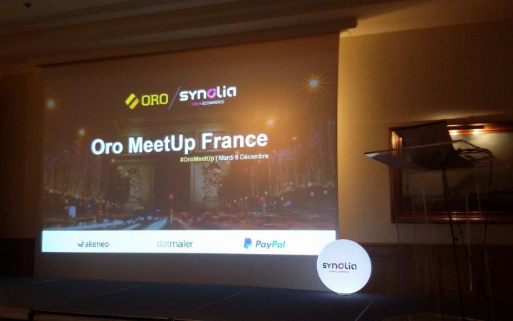 Het podium tijdens de Oro Meetup in Frankrijk. Op het podium hangt een scherm waar de eerste slide van een presentatie te zien is.