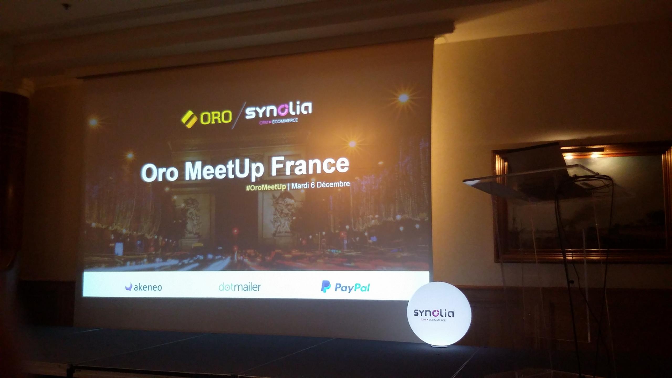 Het podium tijdens de Oro Meetup in Frankrijk. Op het podium hangt een scherm waar de eerste slide van een presentatie te zien is.